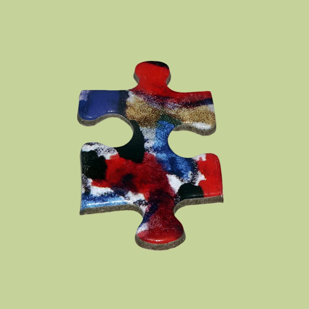 A colorful puzzle piece in red, blue, and black is displayed on a green surface, highlighting its distinct design