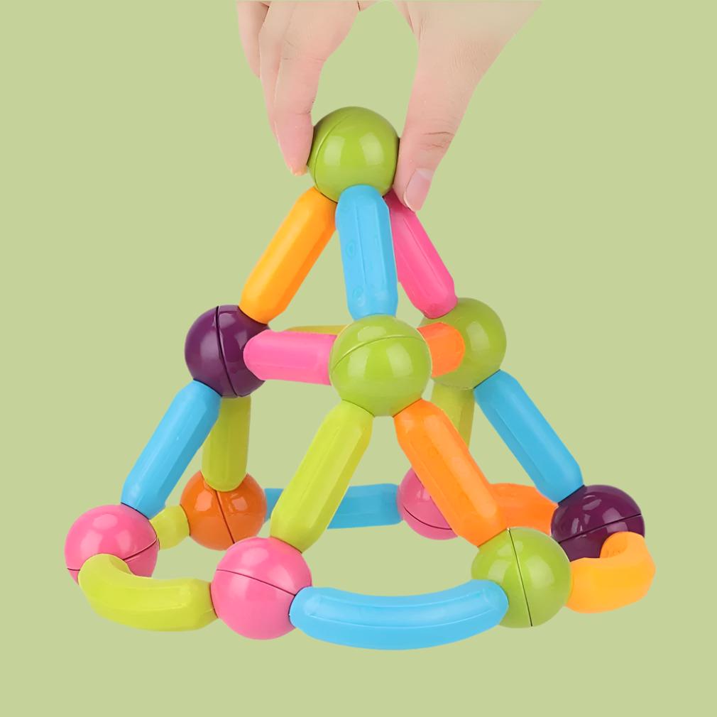 A hand grips a colorful pyramid-shaped toy constructed from magnetic blocks, highlighting its bright hues and engaging form.